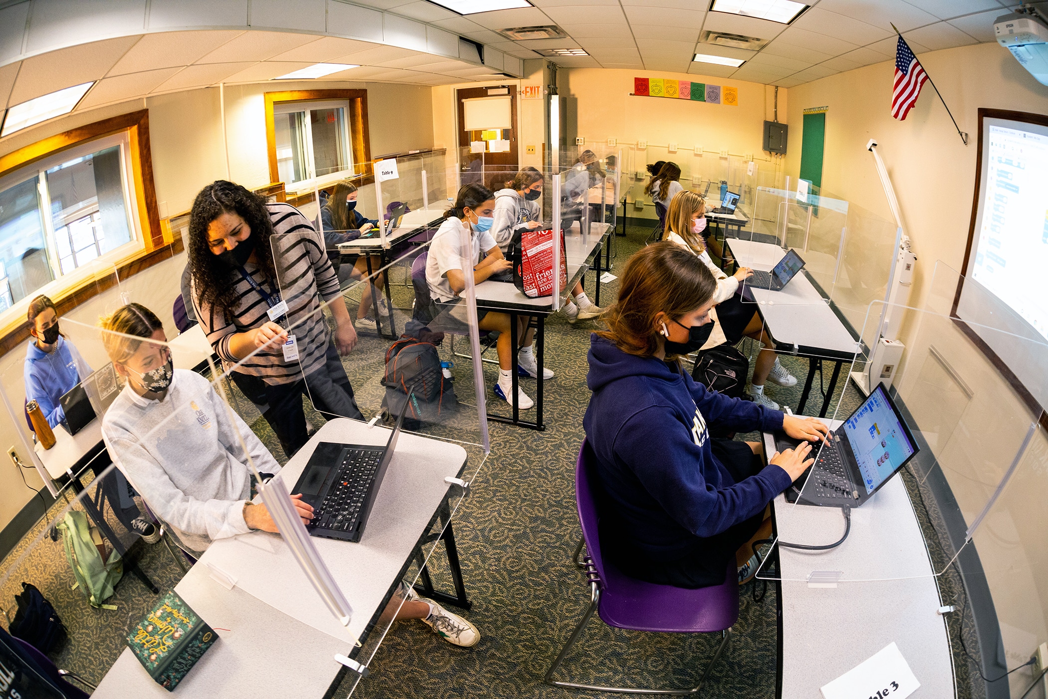 Teacher helps student on a laptop during a computer science class